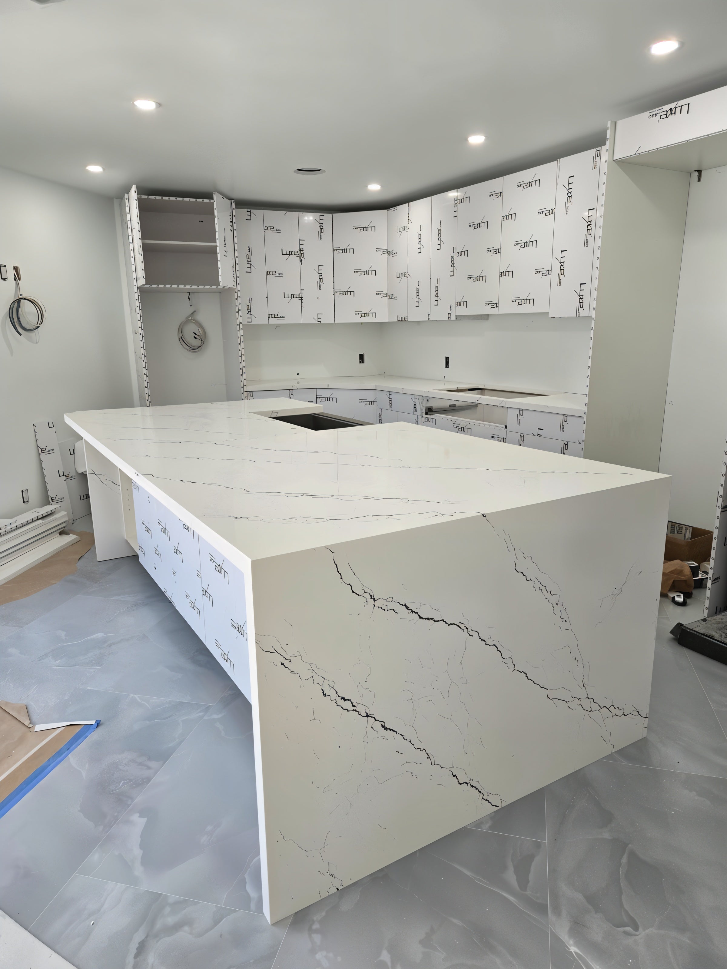 White quartz waterfall island with bold veining in a modern kitchen under renovation.