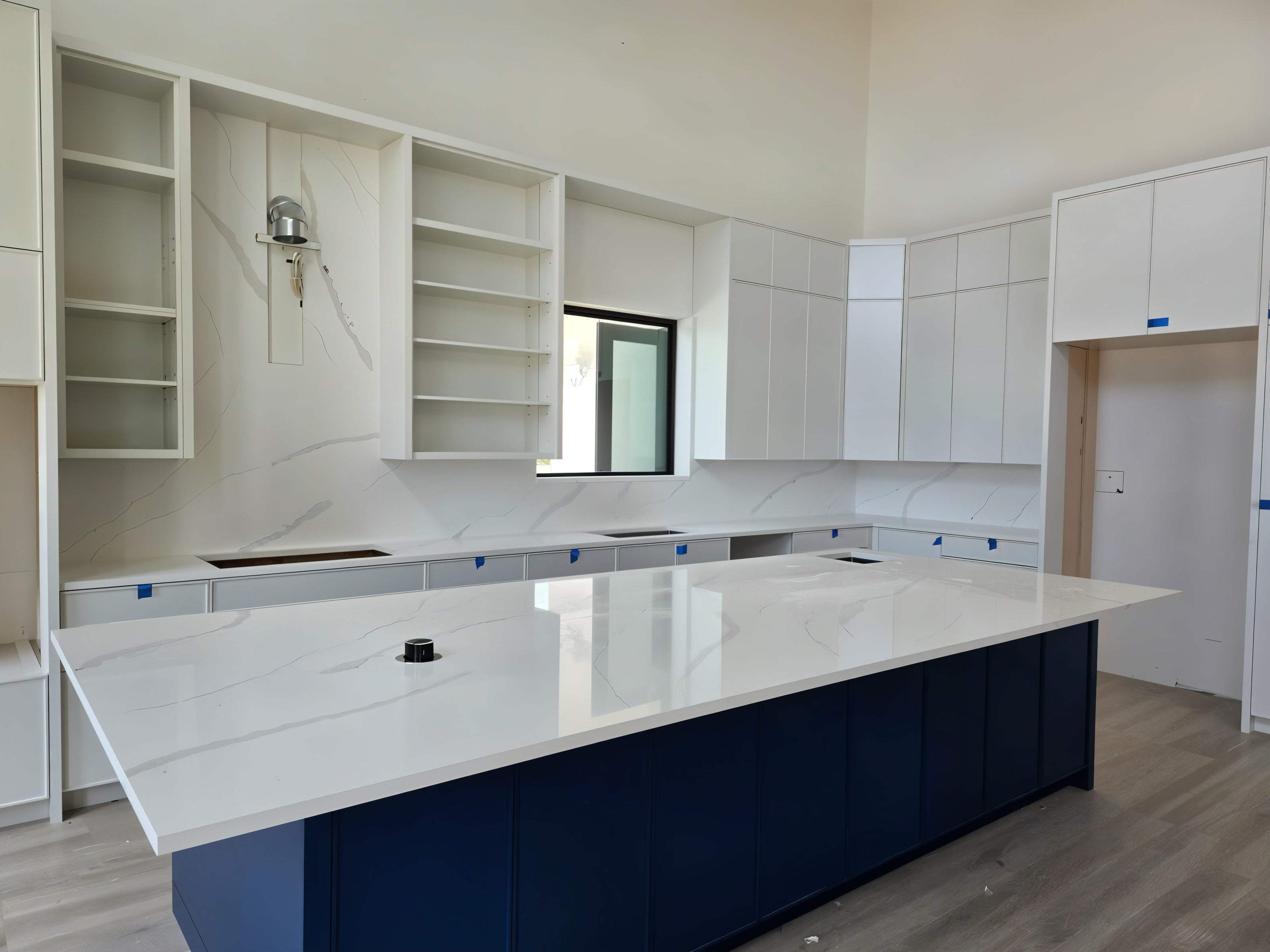 Spacious kitchen featuring white quartz countertops, full quartz backsplash, and navy-blue island base.