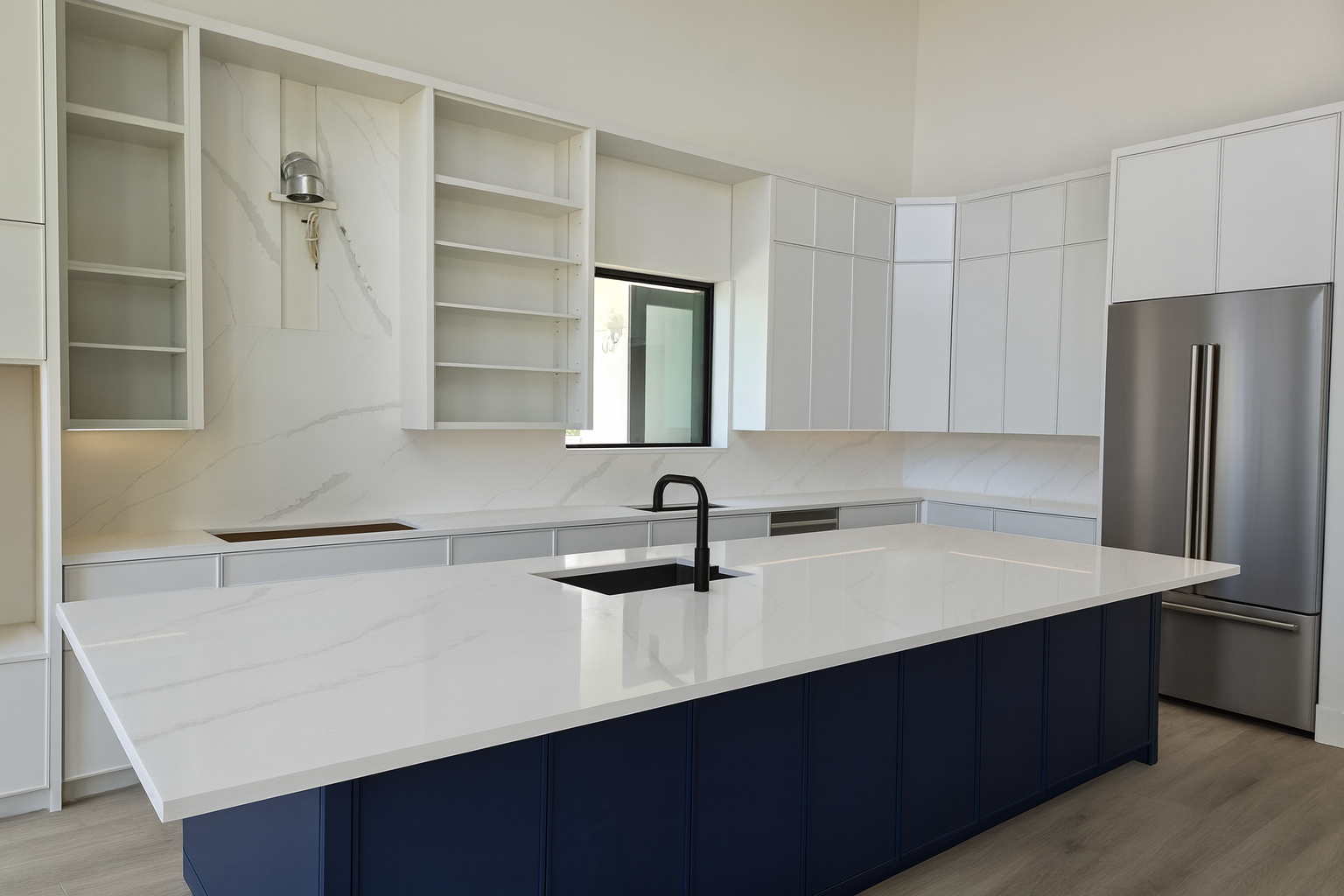 Luxury kitchen design with a white quartz countertop island, navy cabinetry, stainless steel refrigerator, and white shaker cabinets for a modern finish.