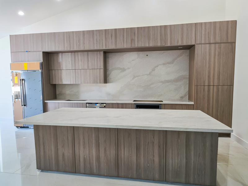 Contemporary kitchen featuring a sleek quartz island and matching quartz backsplash with wood cabinetry.