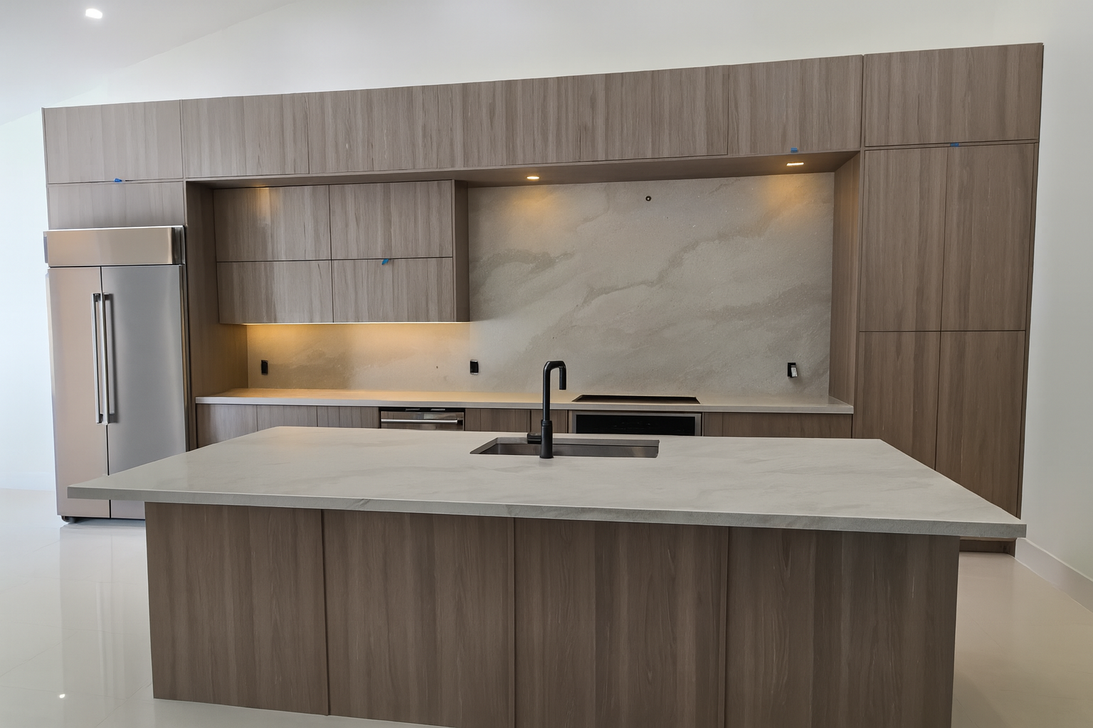 Elegant kitchen with light gray quartz countertops, seamless wood cabinetry, undercabinet LED lighting, and a spacious island with an integrated sink.