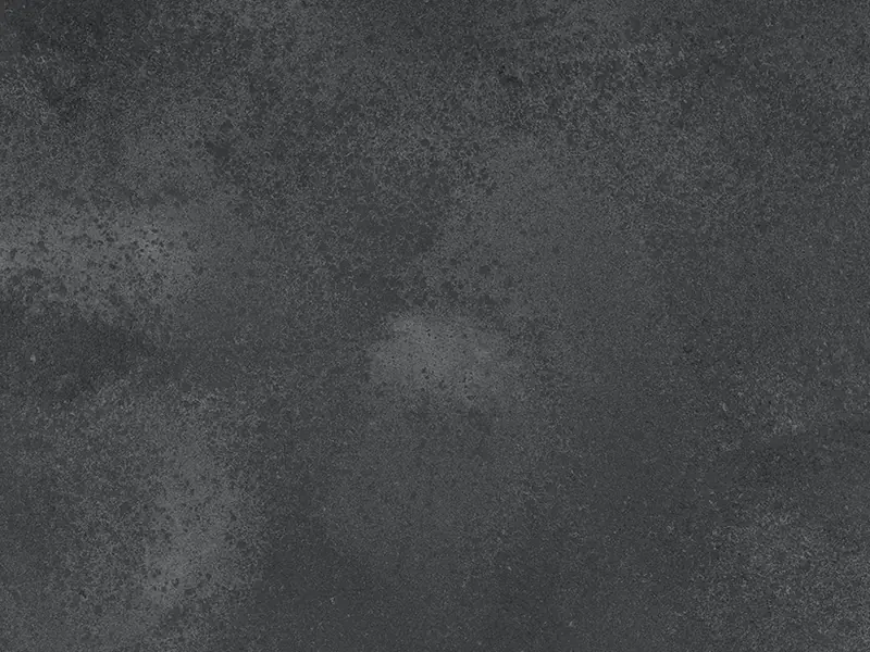 Caesarstone Rugged Concrete quartz swatch: dark gray concrete-look surface with white haze
