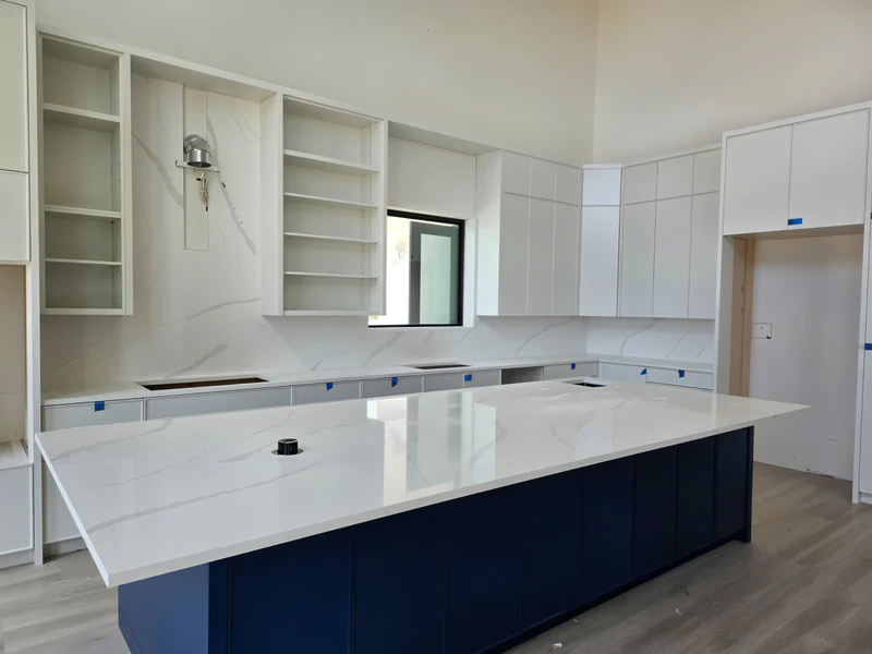 Newly installed white quartz island on a navy base in a kitchen still being finished