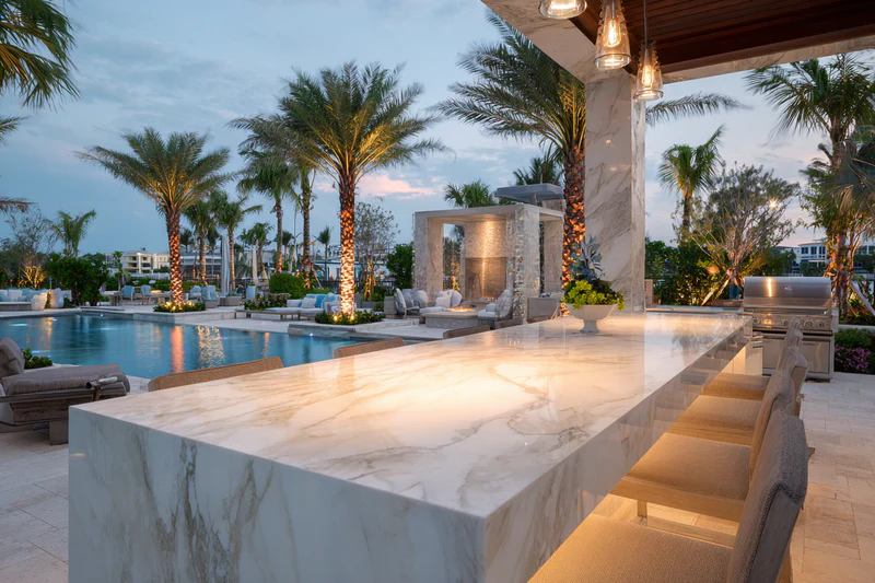 Poolside white marble island with palm trees at dusk
