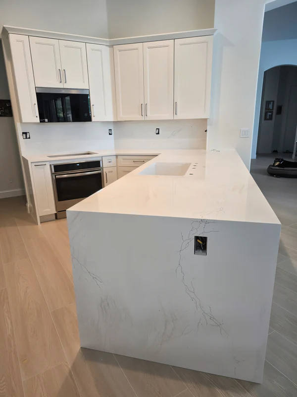 White quartz peninsula with a waterfall end in a white kitchen